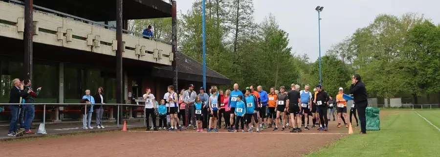 Teilnehmende stellen sich vor dem Start am Stadiongebäude auf